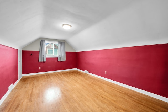 bonus room featuring baseboards, visible vents, vaulted ceiling, and wood finished floors