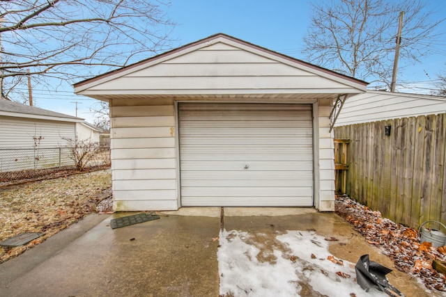 detached garage featuring driveway and fence