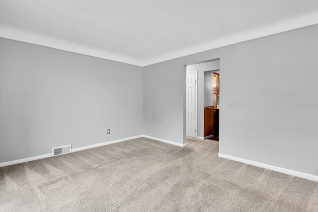 carpeted spare room featuring visible vents and baseboards