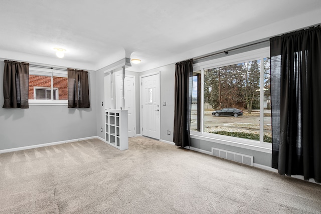 carpeted empty room featuring a healthy amount of sunlight, visible vents, and baseboards