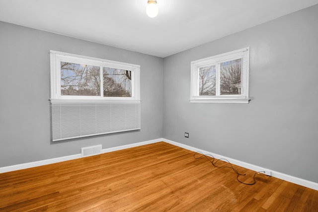 unfurnished room featuring visible vents, baseboards, and wood finished floors