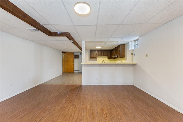 unfurnished living room with a drop ceiling, baseboards, and wood finished floors