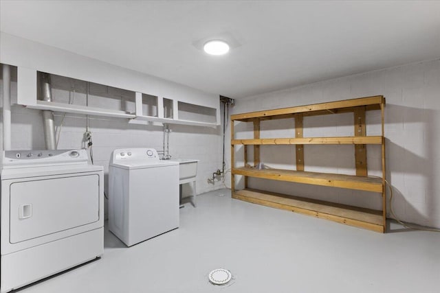 laundry area featuring concrete block wall, laundry area, and separate washer and dryer