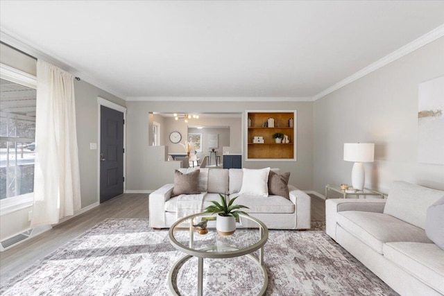 living room featuring visible vents, crown molding, baseboards, and wood finished floors