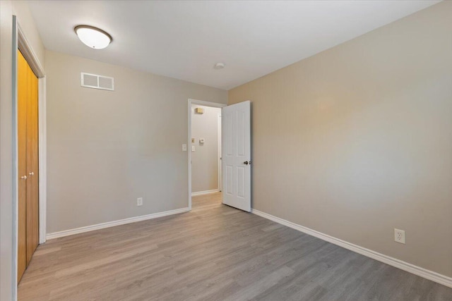 unfurnished room with visible vents, light wood-style flooring, and baseboards