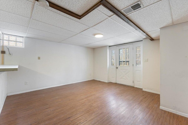 interior space with baseboards, visible vents, a drop ceiling, and wood finished floors