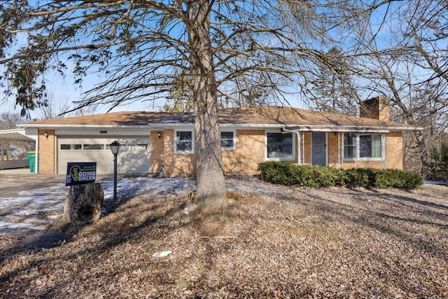 ranch-style home with an attached garage, a chimney, and brick siding