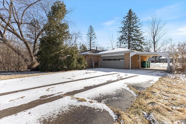 view of side of property featuring driveway, an attached garage, and brick siding