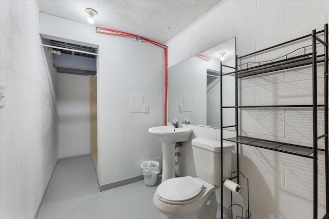 bathroom with toilet, finished concrete floors, baseboards, and a sink