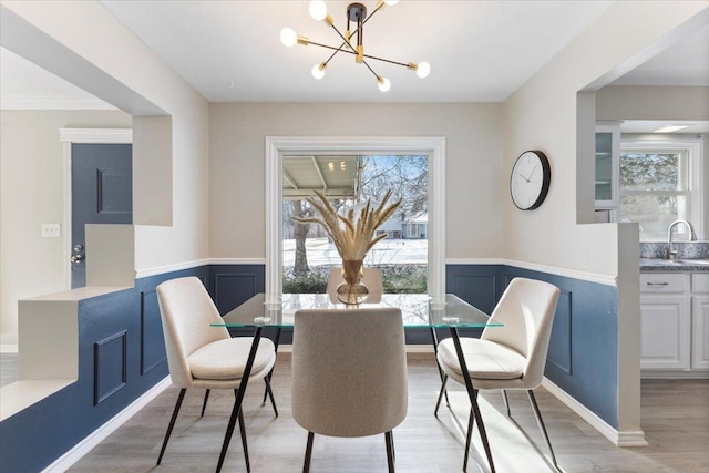 dining space with light wood-style floors, a wainscoted wall, and a healthy amount of sunlight