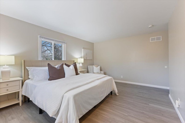 bedroom featuring visible vents, baseboards, and wood finished floors