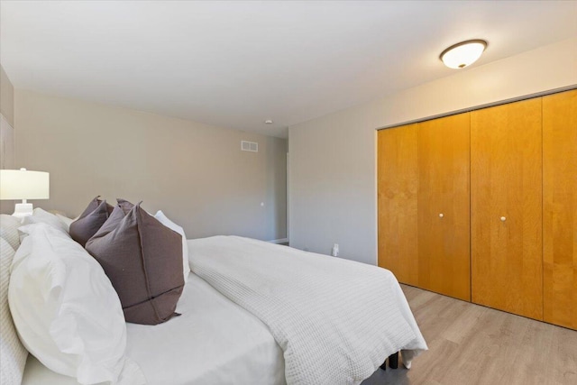 bedroom with a closet, visible vents, and light wood-style flooring