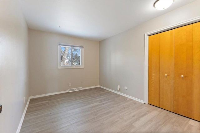 unfurnished bedroom with baseboards, visible vents, and light wood-style floors