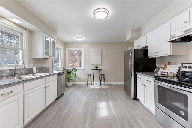 kitchen with light wood-type flooring, white cabinetry, appliances with stainless steel finishes, and a sink