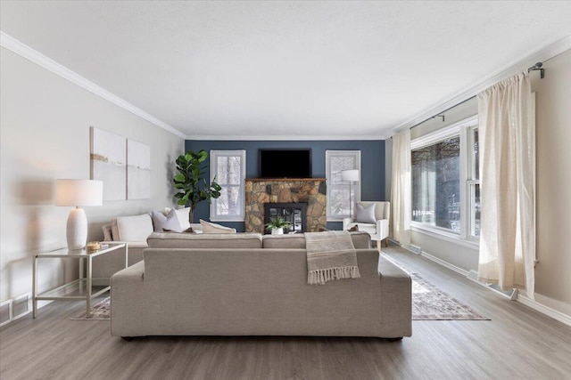 living area with a healthy amount of sunlight, baseboards, wood finished floors, and a stone fireplace