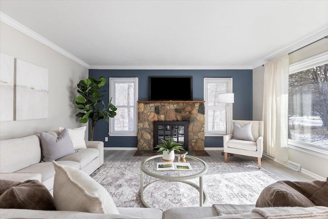 living room with crown molding, a fireplace, visible vents, wood finished floors, and baseboards