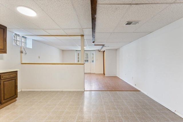 below grade area with a paneled ceiling, visible vents, and baseboards