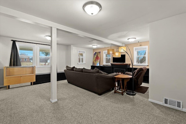 living room with baseboards, visible vents, a lit fireplace, and carpet flooring