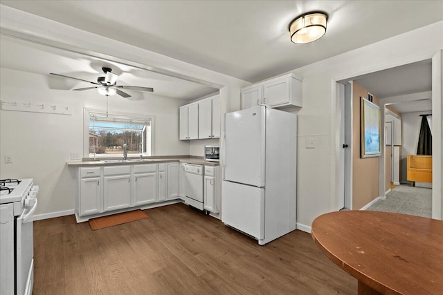 kitchen with white appliances, white cabinetry, a sink, and dark wood-style flooring