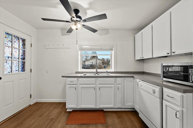 kitchen featuring dark wood-type flooring, stainless steel microwave, white dishwasher, and a sink