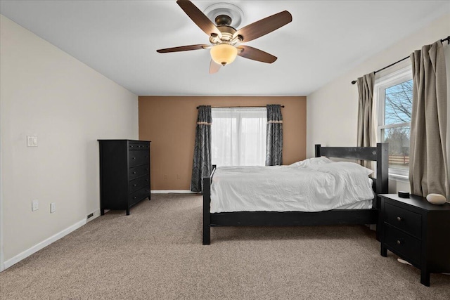 bedroom featuring light carpet, ceiling fan, multiple windows, and baseboards