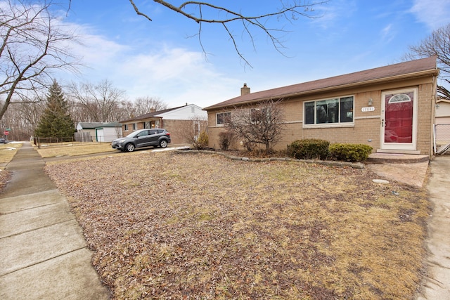 single story home featuring brick siding, fence, and a chimney