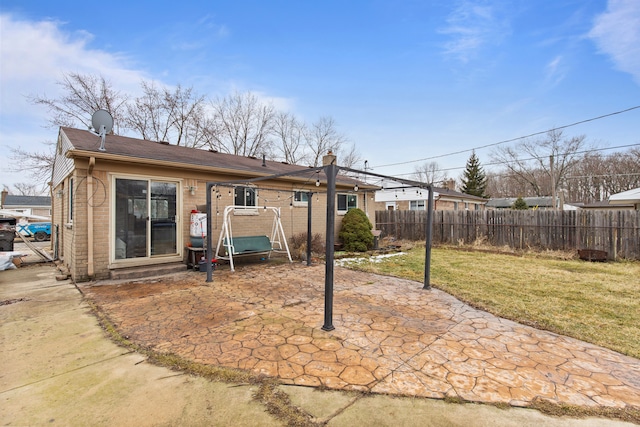 rear view of property featuring entry steps, a patio, brick siding, fence, and a lawn