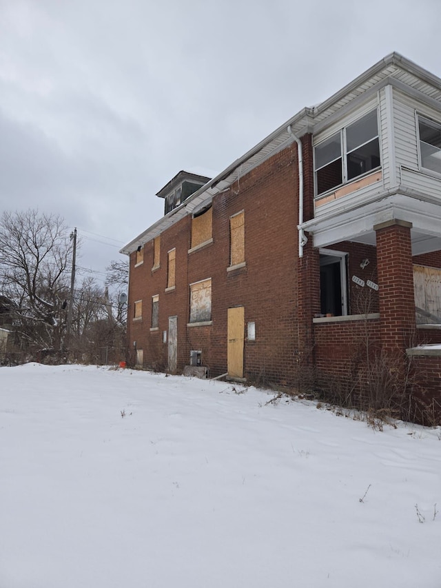 view of snowy exterior featuring brick siding