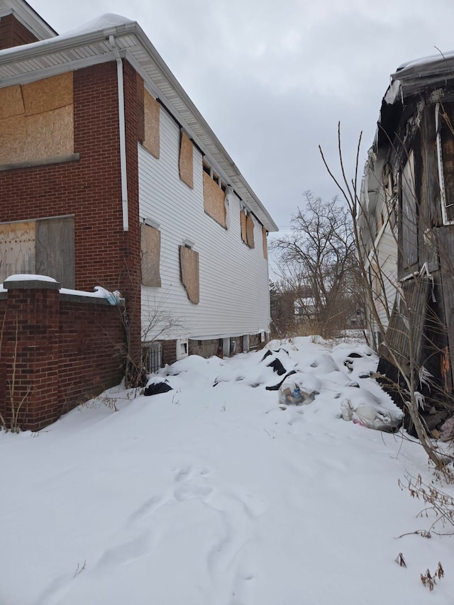 view of snow covered exterior with brick siding