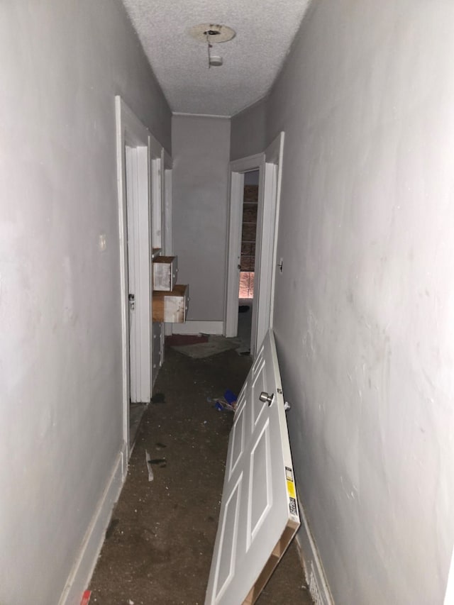 hallway with a textured ceiling and baseboards