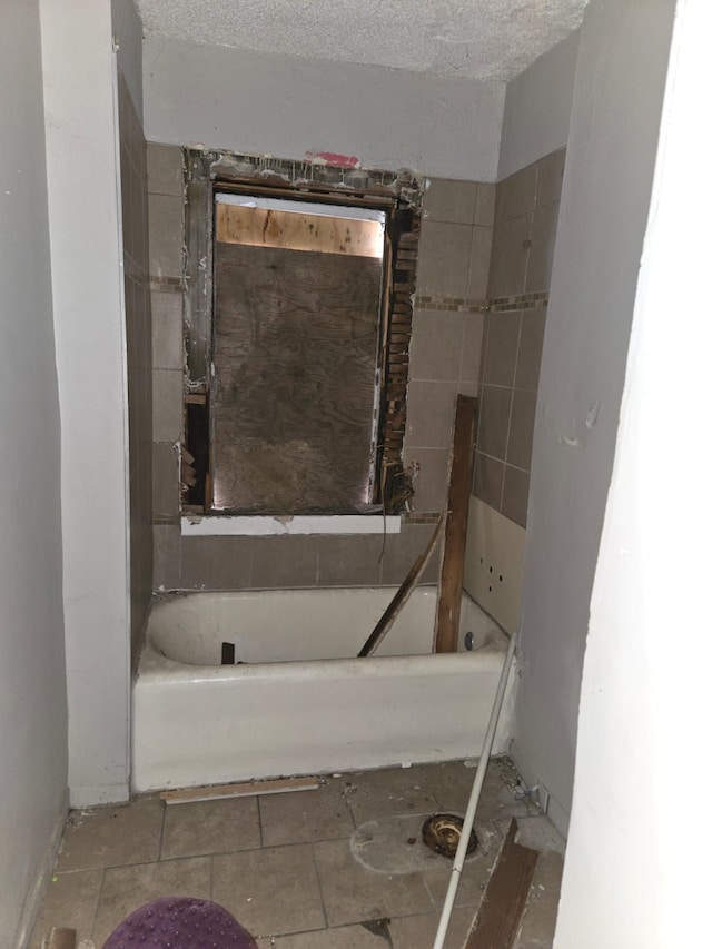 bathroom with a textured ceiling and a washtub