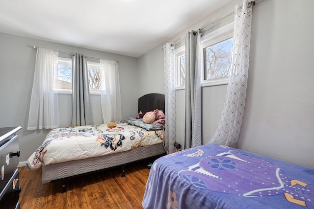 bedroom with multiple windows, wood finished floors, and baseboards