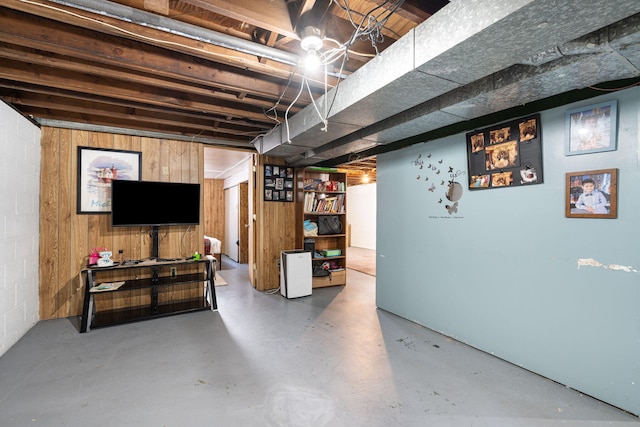 unfinished basement featuring concrete block wall and wood walls