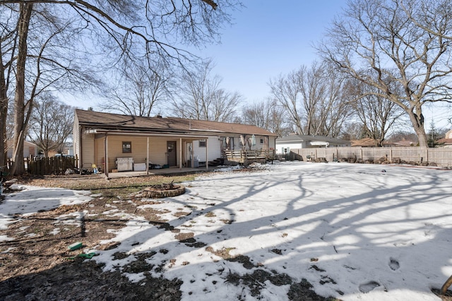 snow covered house featuring a fire pit and fence