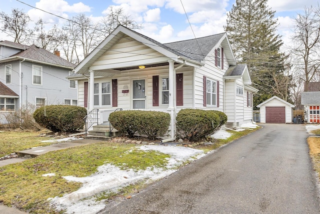 bungalow featuring covered porch, roof with shingles, a detached garage, and an outdoor structure