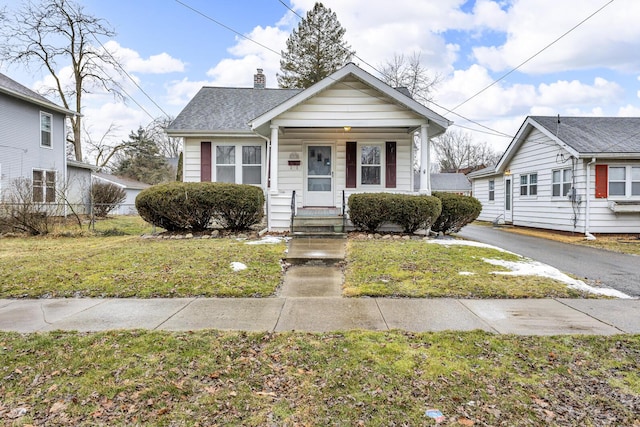 bungalow-style house featuring a chimney, roof with shingles, fence, a porch, and a front yard