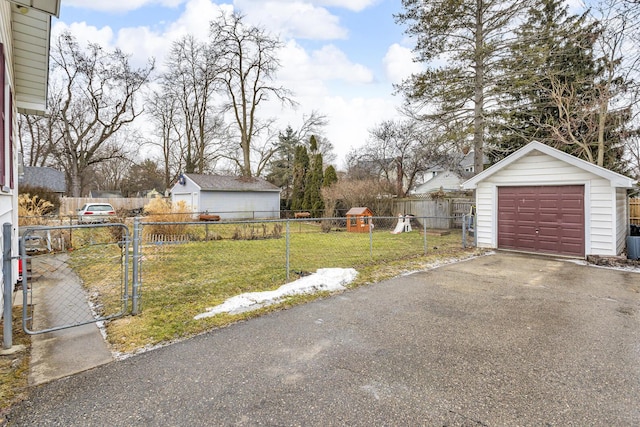 view of yard featuring driveway, a garage, fence private yard, a gate, and an outdoor structure