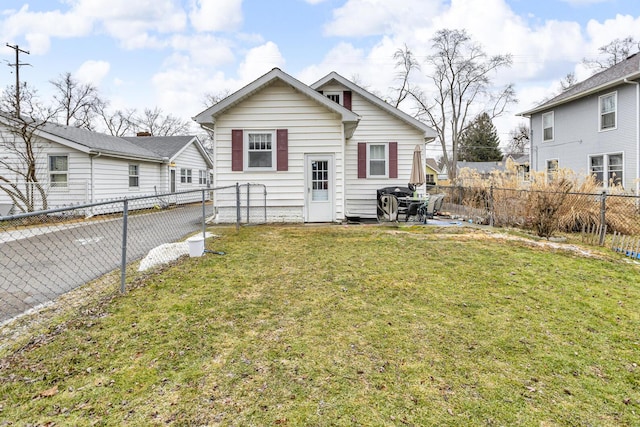 rear view of property featuring a fenced backyard and a lawn