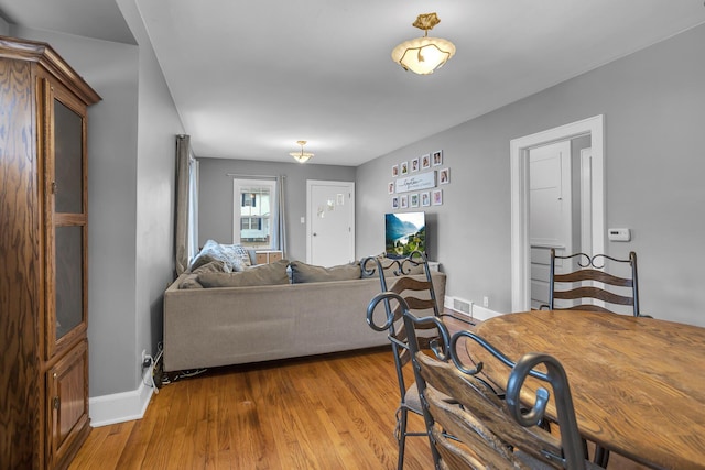 living area featuring visible vents, baseboards, and wood finished floors