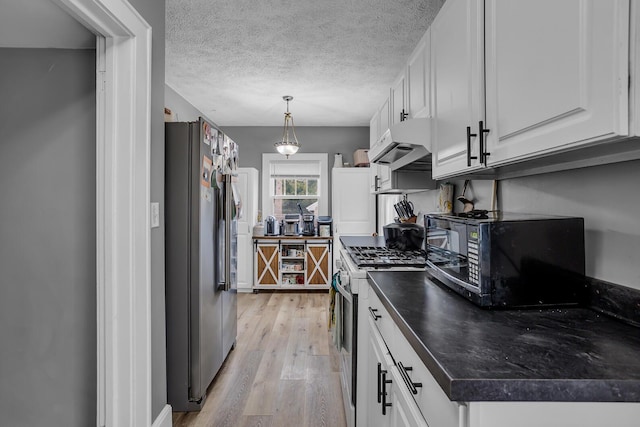 kitchen with range with gas cooktop, dark countertops, freestanding refrigerator, under cabinet range hood, and black microwave