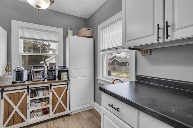 kitchen with dark countertops, white cabinets, and light wood finished floors