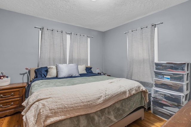 bedroom with a textured ceiling and wood finished floors