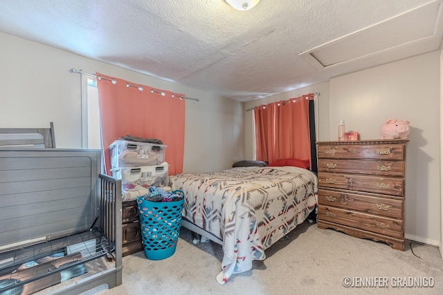 carpeted bedroom featuring attic access and a textured ceiling