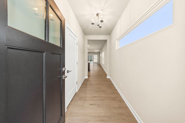 corridor featuring light wood finished floors and baseboards