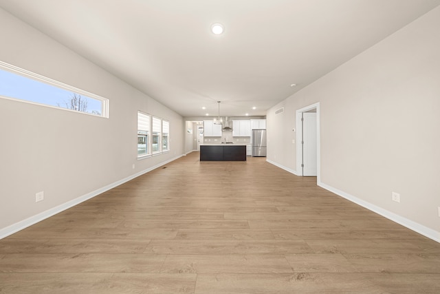 unfurnished living room with light wood-style flooring, visible vents, baseboards, and recessed lighting