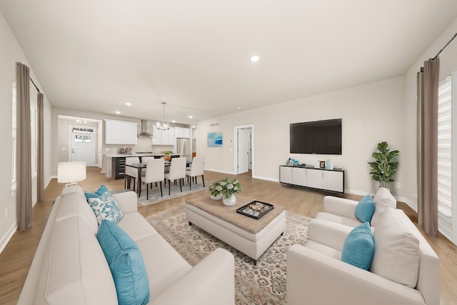 living room with light wood-style floors, baseboards, a chandelier, and recessed lighting