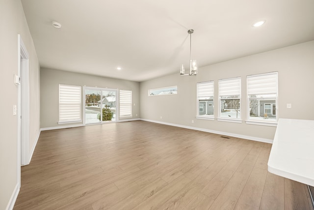 unfurnished living room with recessed lighting, visible vents, an inviting chandelier, wood finished floors, and baseboards