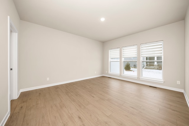 empty room featuring wood finished floors, visible vents, and baseboards