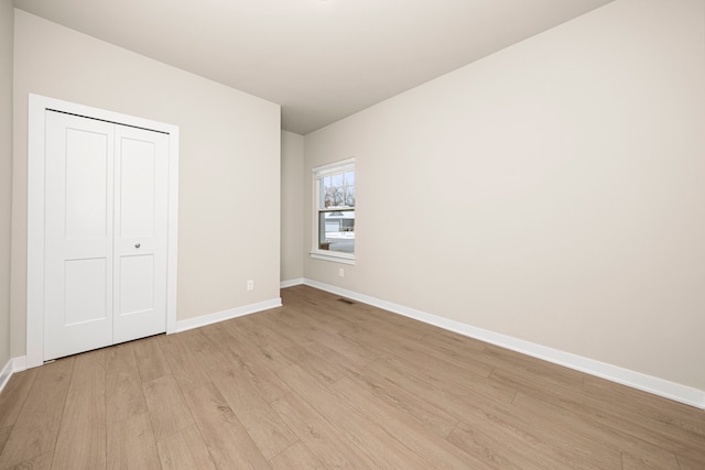 unfurnished bedroom featuring a closet, baseboards, visible vents, and light wood finished floors