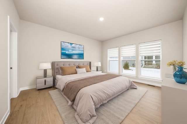 bedroom with light wood-type flooring, visible vents, and baseboards